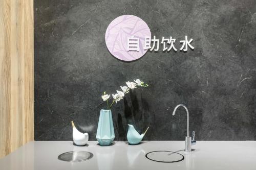 a counter with a sink with vases and a faucet at Hanting Premium Hotel Xiamen Zhongshan Road Pedestrian Street in Xiamen