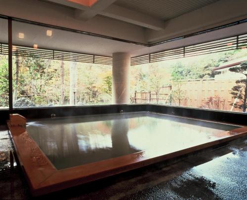 a large pool in a room with a large window at Gensenkan in Nasushiobara