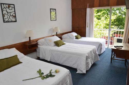 a hotel room with three beds and a window at Hotel Royal in Colonia del Sacramento