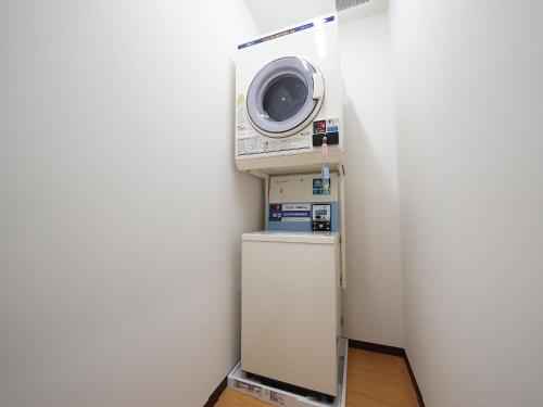 a washing machine sitting on top of a refrigerator at WELLCABIN TENJIN - Male Only in Fukuoka