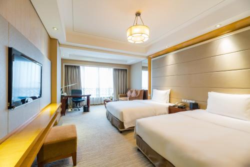 a hotel room with two beds and a flat screen tv at S&N Hotel Jiujiang in Jiujiang