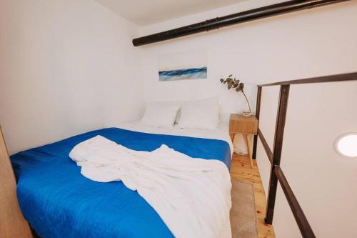 a bedroom with a blue bed with white sheets at In the Middle of everything in Haifa