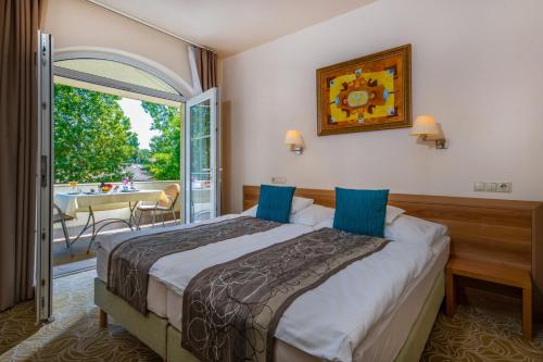 een hotelkamer met een bed en een balkon bij Hotel Kiss in Tata