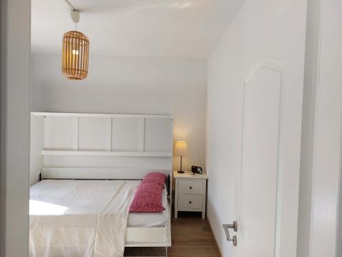 a small bedroom with a white bed and a pink pillow at Schwalbennest in Bad Harzburg