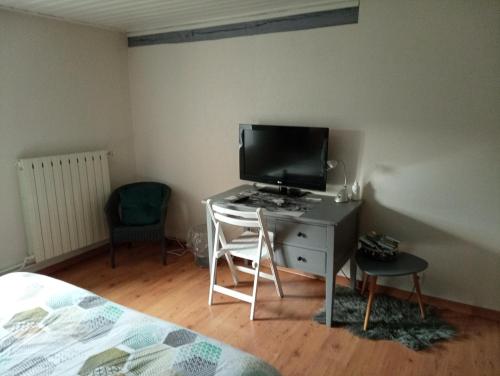 a bedroom with a desk with a tv and a bed at LE JR 70 Relais Motards in Magny-dʼAnigon