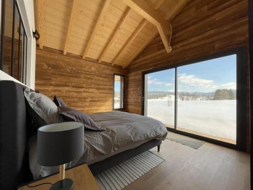 ein Schlafzimmer mit einem Bett und einem großen Fenster in der Unterkunft Unique ! Chalet Grand Standing, la Nature pour vis à vis in Les Rousses