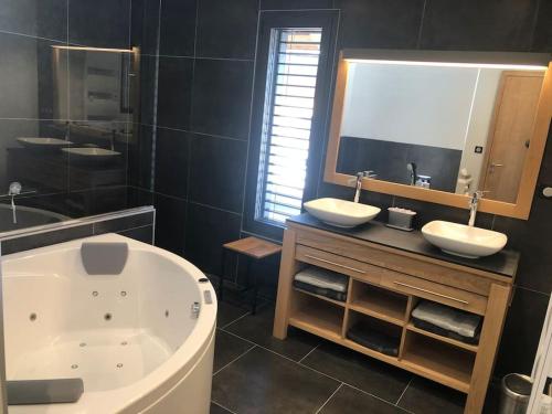 ein Badezimmer mit einer Badewanne, 2 Waschbecken und einem großen Spiegel in der Unterkunft Unique ! Chalet Grand Standing, la Nature pour vis à vis in Les Rousses