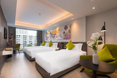 a hotel room with two beds and a table at Maitria Hotel Rama 9 Bangkok - A Chatrium Collection in Bangkok