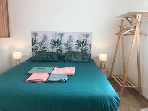 ein grünes Bett mit zwei Handtüchern darüber in der Unterkunft Studio avec Piscine in Saint-Médard-en-Jalles
