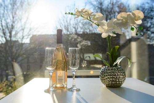 a bottle of wine and two glasses on a table with flowers at The Imp’s Pad - Off Steep Hill - Private Parking in Lincolnshire