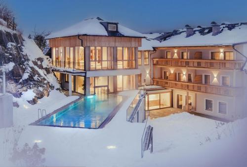 a house with a swimming pool in the snow at Hotel Weissenstein in Sankt Michael im Lungau