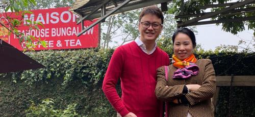 Un uomo e una donna in piedi davanti a un cartello di Maison Teahouse homestay a Ha Giang
