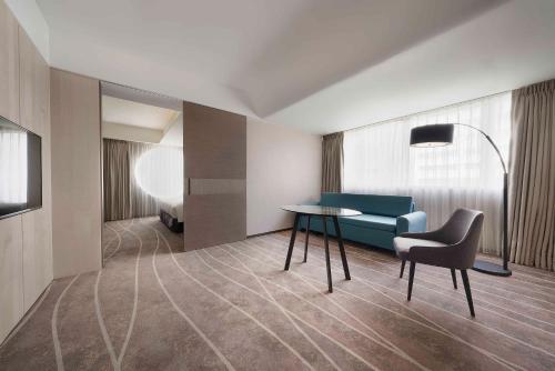 a room with a table and a couch and a bed at ILLUME Taipei in Taipei