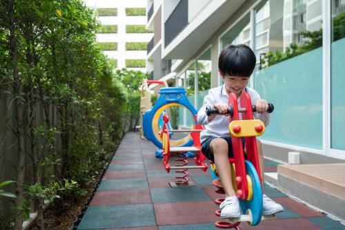 a young boy riding on a toy train on a sidewalk at Maitria Hotel Rama 9 Bangkok - A Chatrium Collection in Bangkok