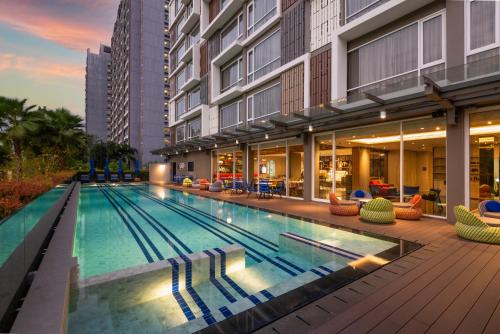 a swimming pool with chairs and a building at Maitria Hotel Rama 9 Bangkok - A Chatrium Collection in Bangkok