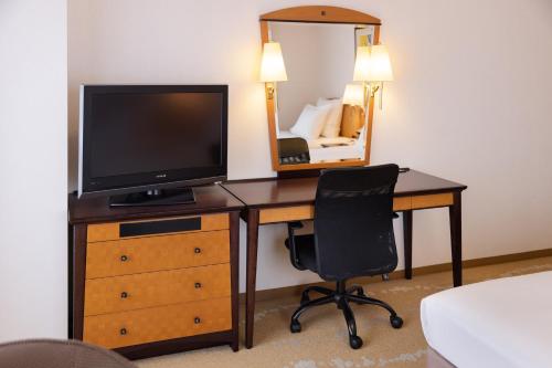 a bedroom with a desk with a television and a chair at ANA Crowne Plaza Toyama by IHG in Toyama