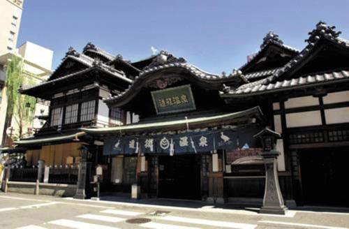 a building with a sign on the front of it at Nest Hotel Matsuyama in Matsuyama