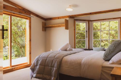 a bedroom with a bed and two windows at Kaimata Cozy in Dunedin