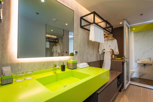 a bathroom with a green sink and a mirror at Maitria Hotel Rama 9 Bangkok - A Chatrium Collection in Bangkok