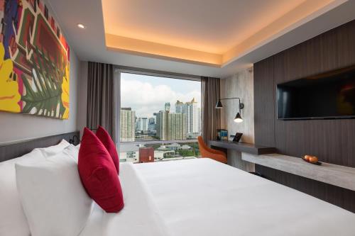 a hotel room with a large bed and a large window at Maitria Hotel Rama 9 Bangkok - A Chatrium Collection in Bangkok