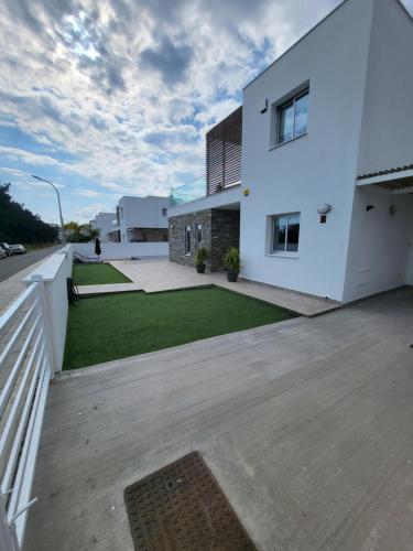 a large white building with a lawn in front of it at Villa utopia in Paphos City