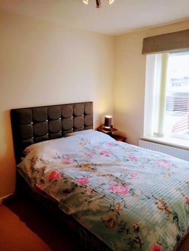 1 dormitorio con 1 cama con edredón de flores y ventana en 2 Bed pet-free cottage, private garden & fell view, en Arlecdon
