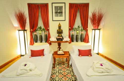 two beds in a room with red curtains at Royal Crown Hotel & Spa in Siem Reap