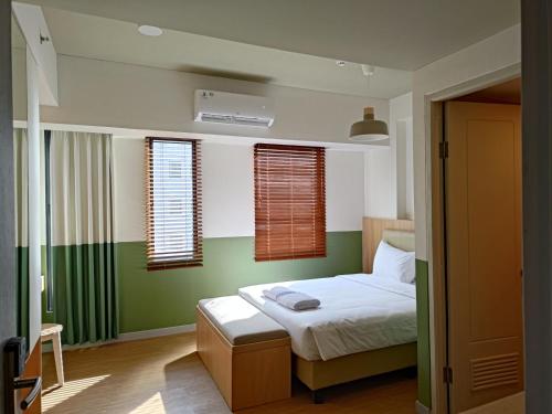 a bedroom with a bed with green walls and windows at Hotel Osaka PIK2 in Tangerang