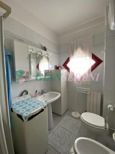 a white bathroom with a sink and a toilet at Campanile in San Vincenzo