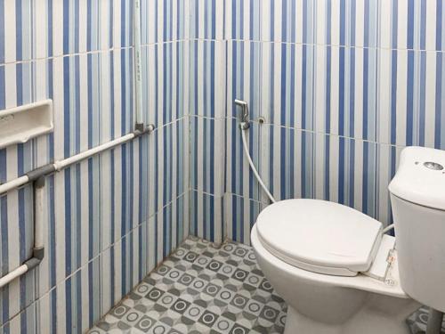 ein Badezimmer mit Toilette und einer blau-weiß gestreiften Wand in der Unterkunft Johje Guest House Medan Mitra RedDoorz in Medan
