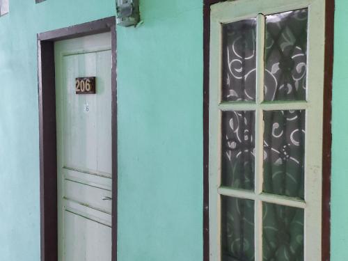 eine Tür und ein Fenster in einer blauen Wand in der Unterkunft Johje Guest House Medan Mitra RedDoorz in Medan
