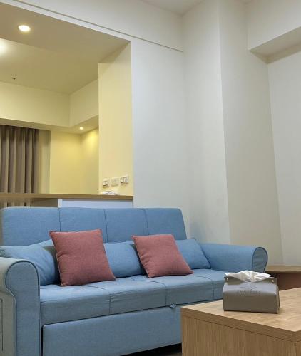 a blue couch with two red pillows in a room at Luxury Studio in the vibrant Kaohsiung Arena MRT in Kaohsiung