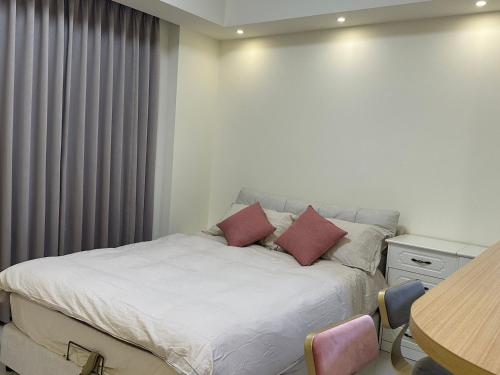um quarto com uma cama com duas almofadas em Luxury Studio in the vibrant Kaohsiung Arena MRT em Kaohsiung