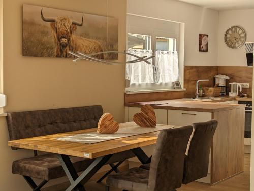 a kitchen with a wooden table with a bull on the wall at Ferienhof-Dachsberg Wohnung Highlander in Bermatingen