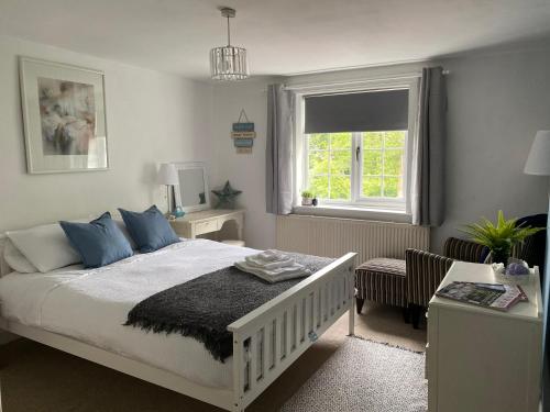 a bedroom with a bed and a chair and a window at Fern Cottage Iden, Rye in Iden