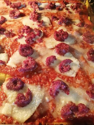 a close up of a pizza with cheese and meat toppings at B&B e Home Restaurant S'ispera Monolocale uso esclusivo in Fonni