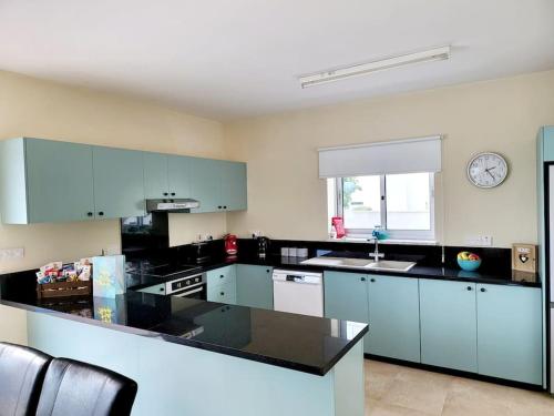 a kitchen with blue cabinets and a clock on the wall at Villa utopia in Paphos City