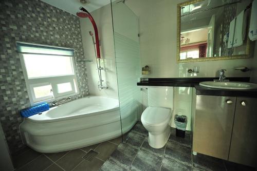 a bathroom with a tub and a toilet and a sink at Yejeon Pension in Gyeongju