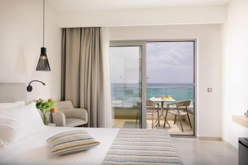 a bedroom with a bed and a view of the ocean at Batis Beach Hotel in Rethymno Town