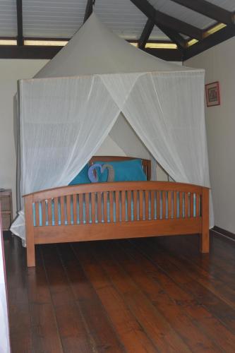 a wooden bed with a canopy in a room at Villa MERAHI ... La villa d'Ange Fare Noa Mymy in Uturoa