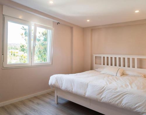 1 dormitorio con cama blanca y ventana en 20 min from BCN- Charming house w/ pool & BBQ area en Cervelló