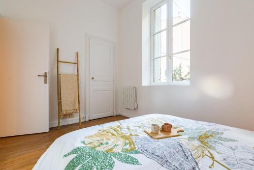 een slaapkamer met een bed met een dienblad en een raam bij Côté Cour - Centre Ville- Calme - Charme - 4 Voyageurs in Dijon