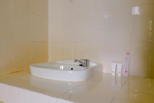 un lavabo blanco en un baño de azulejos blancos en OYO 1784 Hj. Aniek Residence, en Madiun