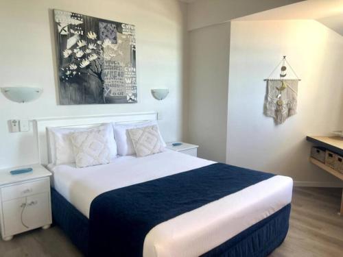 een slaapkamer met een groot bed met blauwe en witte lakens bij Ocean Views - Top floor in Alexandra Headland