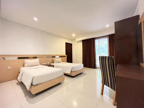 a hotel room with two beds and a desk at Lembah Permai Resort in Sindanglaya