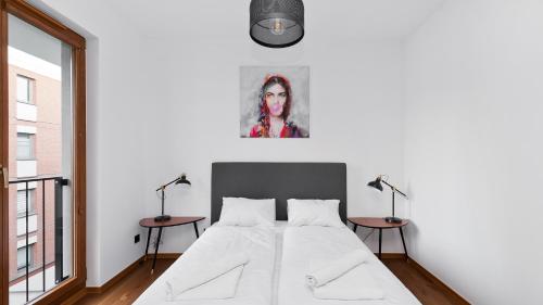 um quarto branco com uma cama e duas mesas em Apartamenty Sun & Snow Rakowicka Podkowa em Cracóvia