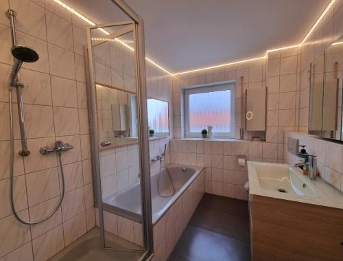 y baño con ducha, bañera y lavamanos. en Ferienhaus im Luftkurort, en Schömberg