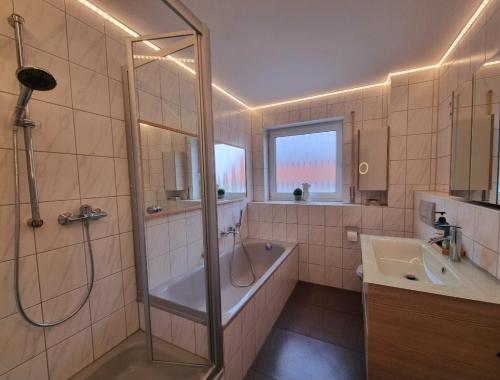 een badkamer met een douche, een bad en een wastafel bij Ferienhaus im Luftkurort in Schömberg