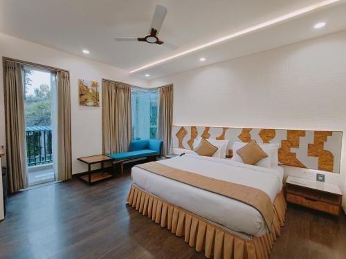 デヘラードゥーンにあるAtaraxia Crestmont Resort & Spaのベッドルーム(大型ベッド1台、青い椅子付)
