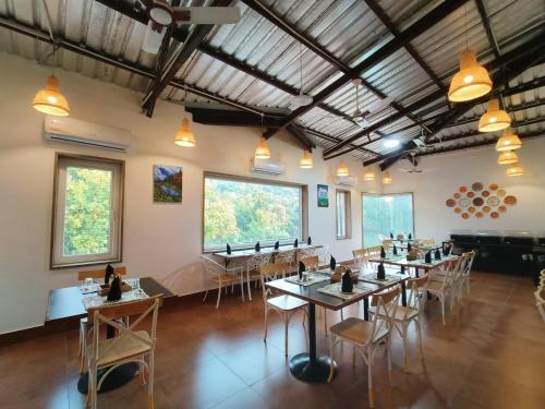 een eetkamer met tafels en stoelen en ramen bij Ataraxia Crestmont Resort & Spa in Dehradun